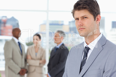 Serious businessman with a stern look standing in front of his c