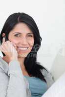 Smiling woman phoning while sitting on a sofa