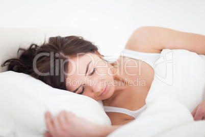 Brunette woman lying on a bed while sleeping