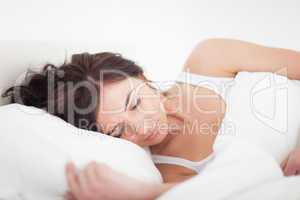 Brunette woman lying on a bed while sleeping