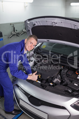 Mechanic leaning on a car while looking at camera