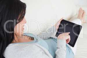 Woman laying on a sofa while holding a tactile tablet