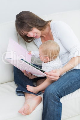 Baby holding a book with a mother