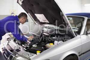 Mechanic typing on a computer while looking it