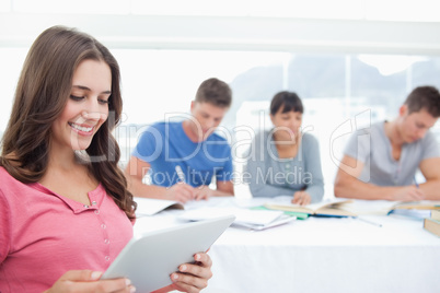 A smiling woman in front of her friends on her tablet