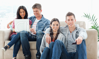 A couple sitting on the ground with a remote while another coupl