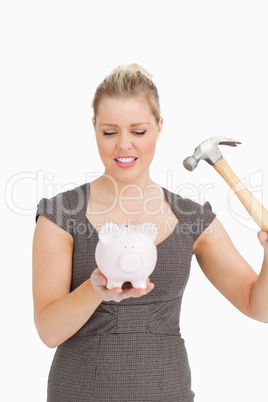 Serious woman with a piggy bank and a hammer