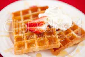 Waffles with whipped cream and strawberry and syrup