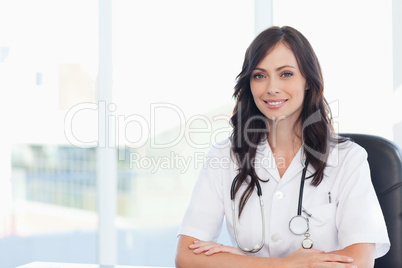 Young doctor sitting on a black chair at the desk with her arms