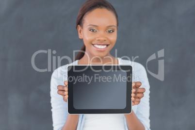 Black woman holding a tablet computer next to a blackboard