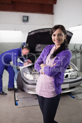 Woman smiling with arms crossed next to a car