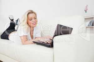 Woman working on a laptop while lying