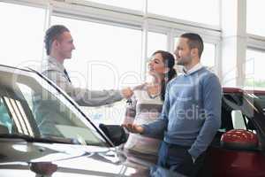 Smiling salesman handing keys to a couple