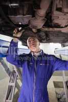 Mechanic illuminating a car with a flashlight