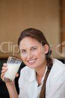 Woman holding a glass of milk while smiling