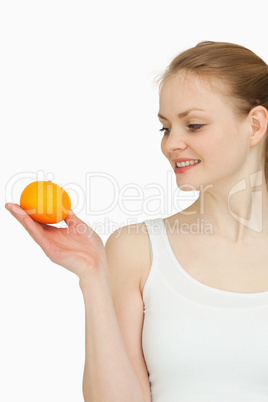 Smiling woman presenting a tangerine while looking at it