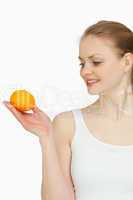 Smiling woman presenting a tangerine while looking at it