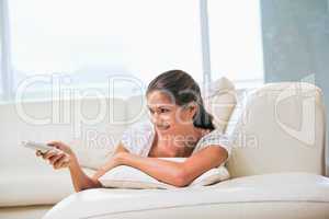 Woman lying on a sofa while holding a remote