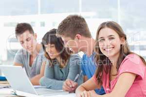Three students look into the laptop as the fourth student looks