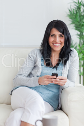 Woman holding a telephone while relaxing on a sofa