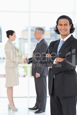 Young businessman standing upright in front of colleagues shakin