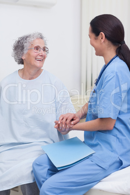 Nurse sitting on bed with a patient
