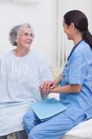 Nurse sitting on bed with a patient