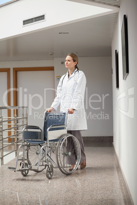Serious doctor pushing a wheelchair in the corridor