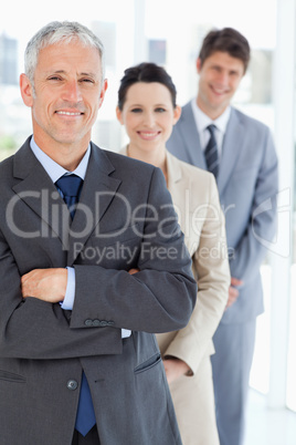 Smiling mature businessman standing upright in front of his youn