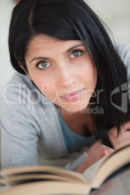 Woman reading a book as she lays on a white sofa