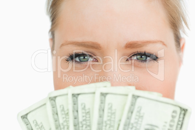 Close-up of a woman face hidden with dollars banknotes