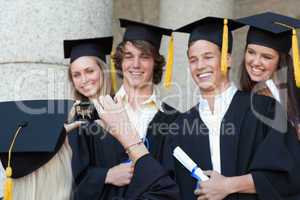 Close-up of a graduate taking a picture of her smiling friend