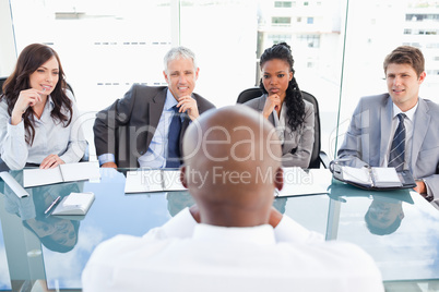 Four business people sitting at the desk while attentively liste