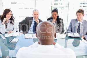 Four business people sitting at the desk while attentively liste