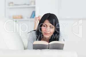 Woman reading a book while lying on a couch