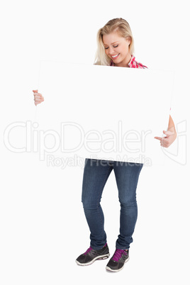 Smiling blonde woman pointing at a blank sign