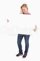 Smiling blonde woman pointing at a blank sign