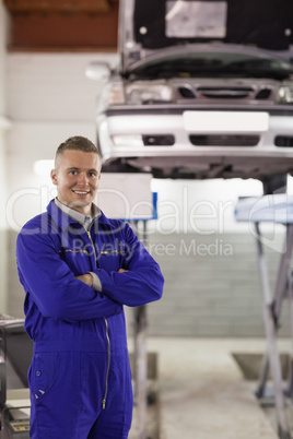 Smiling mechanic looking at camera next to a car