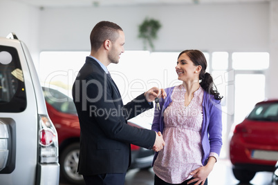 Woman shaking the hand of a salesman while receiving car keys
