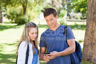 Close-up of a student showing his smartphone to a girl