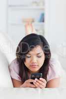 Woman lying on a sofa while looking at a phone