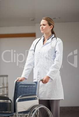 Serious female doctor pushing a wheelchair