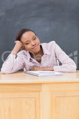 Black woman leaning on desk while looking at camera