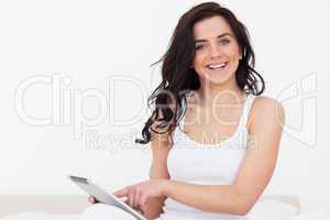 Smiling brunette woman sitting while touching her tablet pc
