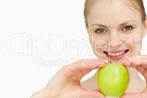 Joyful blond-haired woman presenting an apple