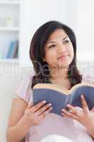 Woman sitting on a sofa while she holds a book