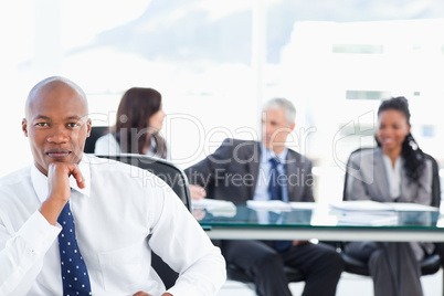 Young and confident manager looking at the camera while his team