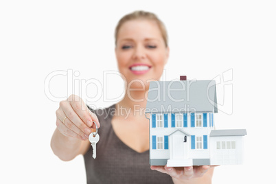 Woman blurred showing a model house and a key