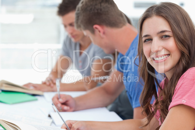 A smiling woman looking at the camera as her friends sit in the