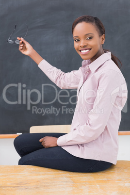 Teacher sitting on desk showing the blackboard